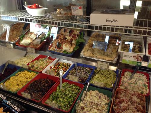 A display case filled with various colorful salads and dishes, including pasta, grains, and vegetables.