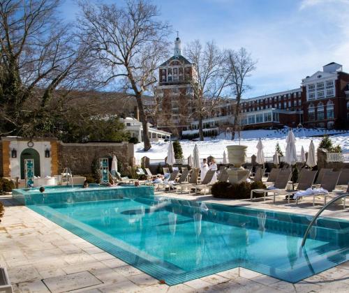 A serene outdoor pool area with lounge chairs, surrounded by trees and a historic building in the background.