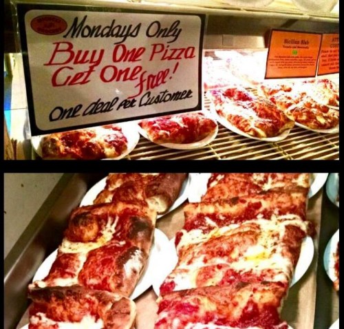 Sign promoting a Monday special: Buy one pizza, get one free, with pizzas displayed in the background.