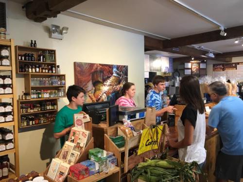 A busy store interior with shelves of products, a checkout counter, and customers interacting with staff.