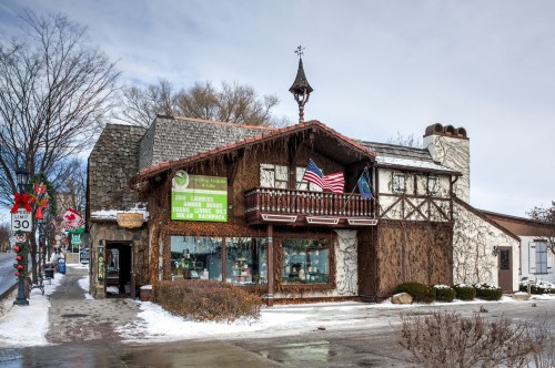 Charming building with a wooden balcony, flags, and festive decorations, set in a snowy winter landscape.