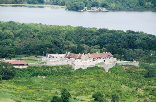 Aerial view of a historic stone fort surrounded by greenery and a river in the background.