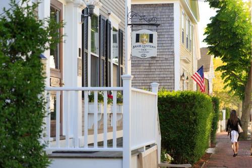 A charming street scene with a white fence, a sign for "Brass Lantern," and a girl walking past American flags.
