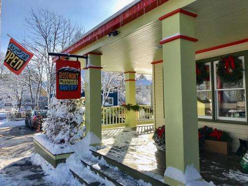 A charming bakery entrance decorated for the holidays, with snow-covered surroundings and a bright "Open" sign.