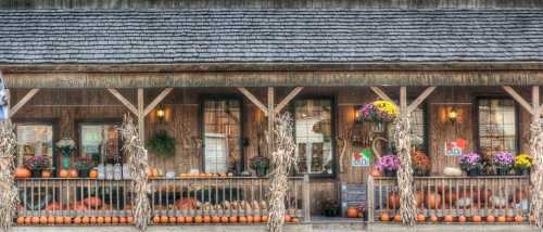 A cozy porch decorated with pumpkins, flowers, and autumn decor, creating a warm fall atmosphere.