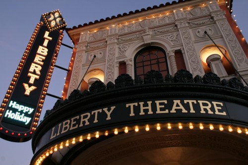 The Liberty Theatre sign illuminated at dusk, featuring ornate architecture and festive holiday decorations.