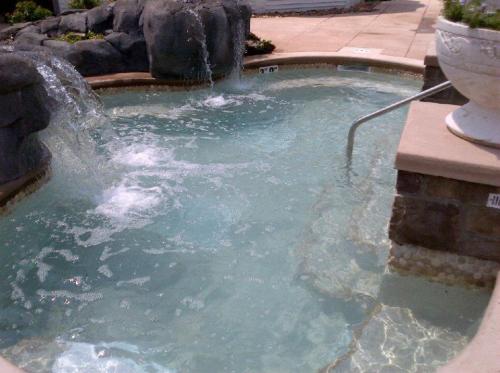 A relaxing hot tub with bubbling water, surrounded by stone features and a decorative planter.