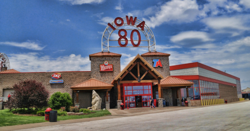 Iowa 80 truck stop featuring a Dairy Queen, Wendy's, and a large sign against a blue sky with clouds.