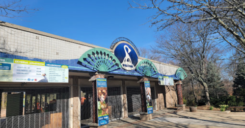 Entrance of a building with a sign reading "Welcome," featuring decorative elements and banners on either side.