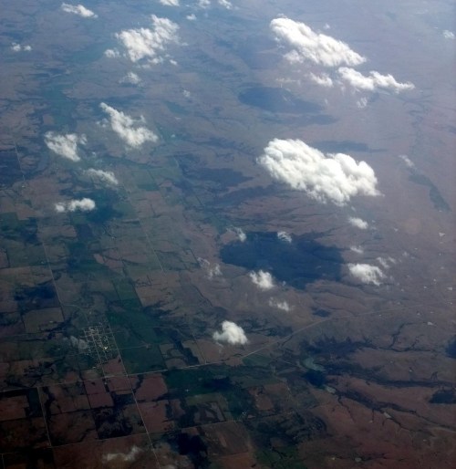 Aerial view of patchwork fields and scattered clouds over a landscape.