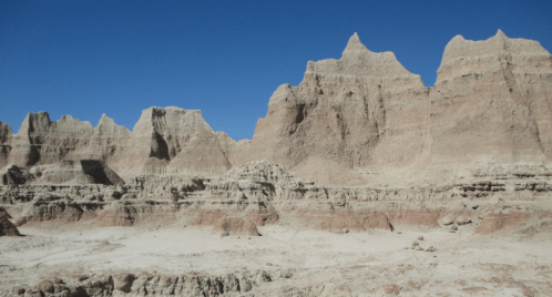 A rugged landscape of layered rock formations under a clear blue sky.