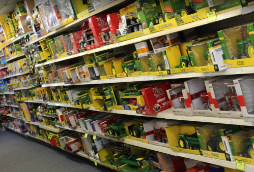 A colorful display of toy tractors and farm equipment on shelves in a store, showcasing various models and brands.