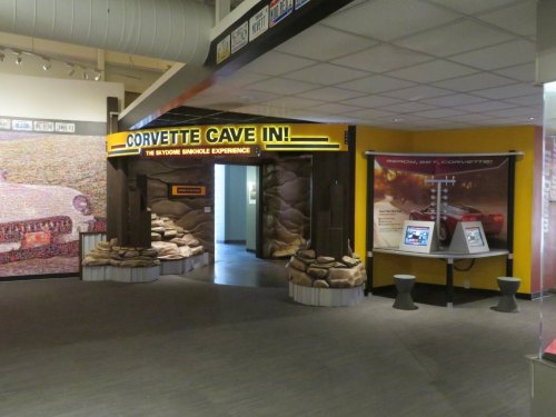 Entrance to the "Corvette Cave In!" exhibit, featuring a cave-like structure with sandbags and informational displays.