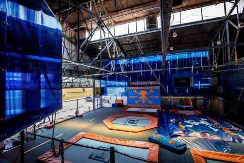 Indoor trampoline park featuring colorful trampolines, a foam pit, and safety mats in a spacious, well-lit area.