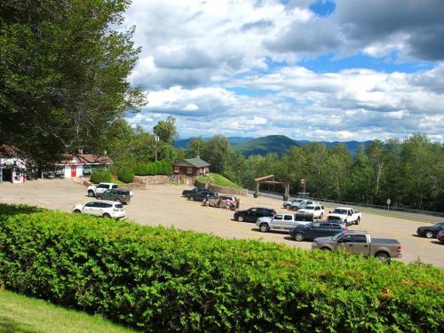 A scenic view of a parking lot surrounded by greenery and mountains under a partly cloudy sky.