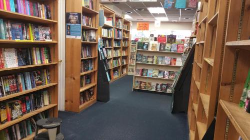 A cozy bookstore aisle lined with wooden shelves filled with various books, creating a welcoming reading atmosphere.