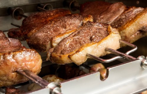 Close-up of skewered meats roasting on a grill, showcasing golden-brown crusts and juicy textures.