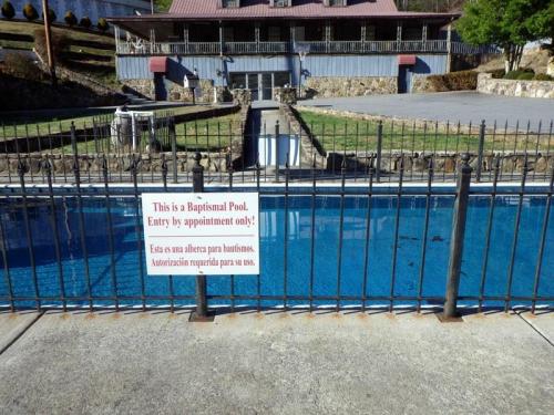 A fenced baptismal pool with a sign stating "Entry by appointment only" in English and Spanish.
