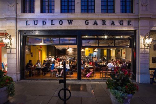 A bustling restaurant, Ludlow Garage, with diners enjoying meals inside and outdoor seating visible.