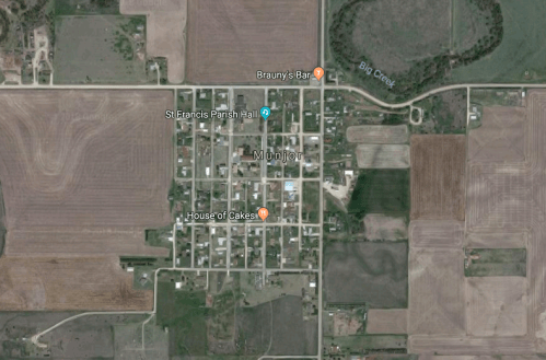 Aerial view of the small town of Munjor, featuring streets, buildings, and surrounding farmland.