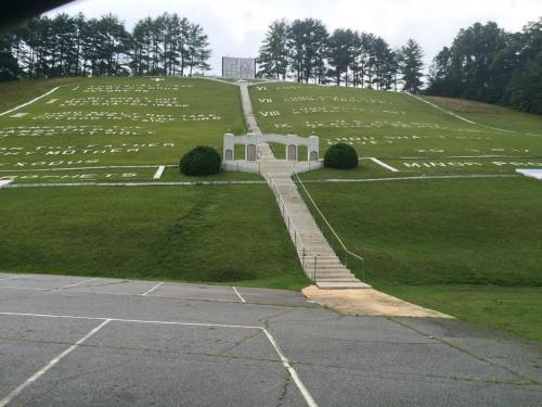 A grassy hill with large white letters and numbers, featuring a staircase leading up to a stone structure at the top.