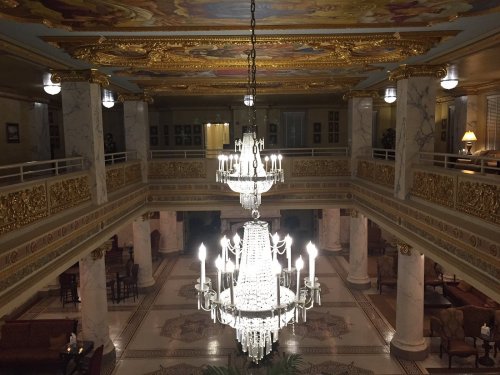 Elegant interior of a grand hall featuring a large chandelier and ornate gold detailing on the walls and ceiling.