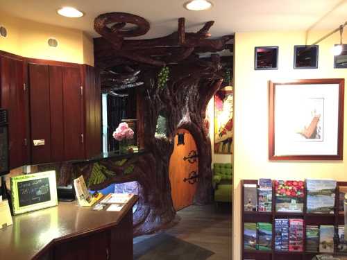 A cozy reception area featuring a tree-like structure, wooden accents, and a welcoming entrance.