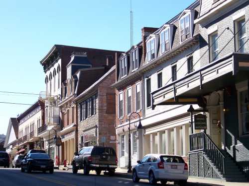 A quaint street lined with historic buildings and parked cars under a clear blue sky.