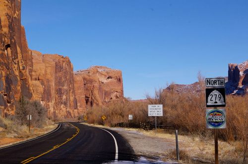A scenic road leads through red rock formations, with a sign for North 279 and a scenic byway marker.