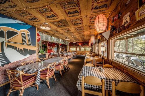 Cozy restaurant interior with checkered tables, wooden decor, and large windows overlooking nature. Warm, inviting atmosphere.