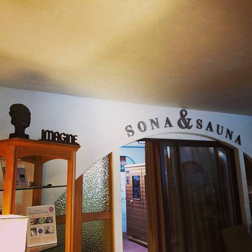 Interior of a wellness space featuring a sauna, wooden decor, and a sign reading "Sona & Sauna."