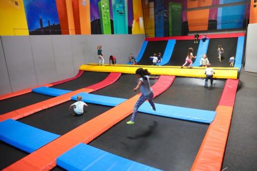 Children jumping and playing on colorful trampolines in a vibrant indoor trampoline park.