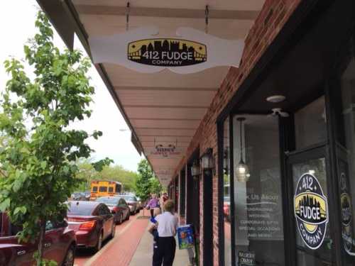 A street view of a storefront with a sign for "412 Fudge Company" and a person walking by.