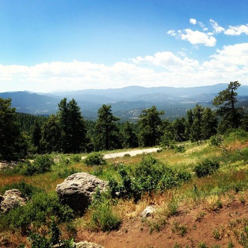 A scenic view of rolling hills and trees under a blue sky with scattered clouds.