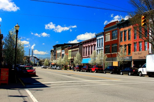 A vibrant street lined with colorful historic buildings and blooming trees under a bright blue sky.