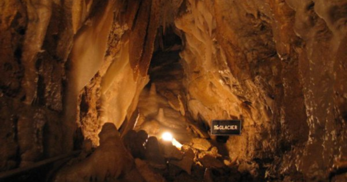 A dimly lit cave with glistening rock formations and a sign labeled "The Glacier" in the foreground.