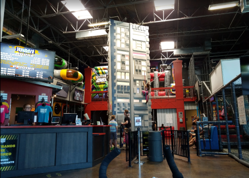 Indoor play area featuring climbing structures, slides, and a reception desk with children playing in the background.