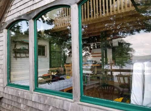 A cozy cabin with large windows reflecting a serene lake view and wooden interior furnishings.
