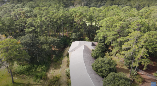 Aerial view of a house surrounded by dense green trees and forest.
