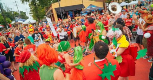 A lively crowd in colorful costumes celebrates at an outdoor event, with music and festivities all around.