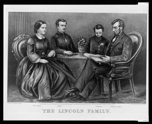 A historic illustration of the Lincoln family seated around a table, with Abraham Lincoln reading and family members listening.