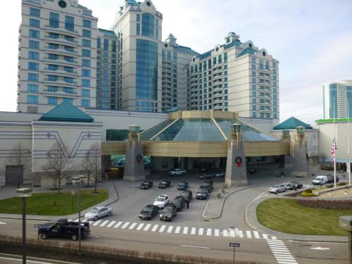 A large hotel and casino building with a glass entrance, surrounded by parked cars and a landscaped area.