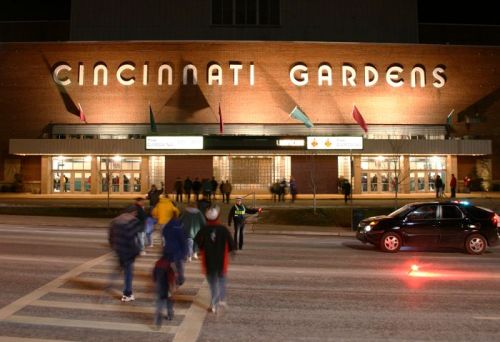 People walking towards Cincinnati Gardens at night, with the building's name illuminated above the entrance.