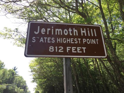 Sign for Jerimoth Hill, stating it is the state's highest point at 812 feet, surrounded by trees.