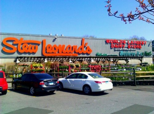 Exterior of Stew Leonard's store, featuring colorful signage and parked cars in front.