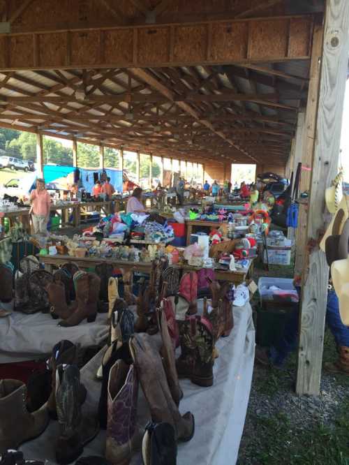 A bustling outdoor market with tables filled with various items and cowboy boots in the foreground.