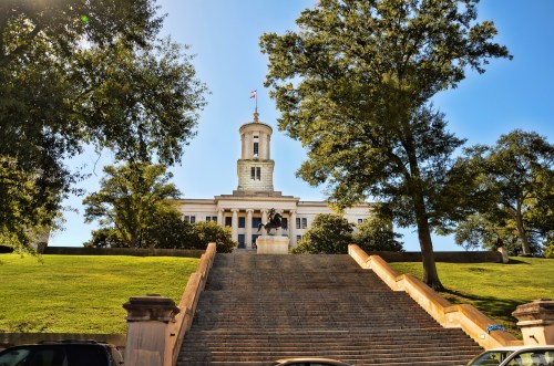 The Tennessee State Capitol building, featuring a tall tower, surrounded by trees and steps leading up to it.