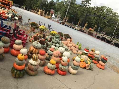 A variety of stacked pumpkins in different colors and sizes, arranged in a festive outdoor setting.