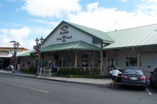 Exterior of Parker Ranch Store with a green roof, festive decorations, and a parked car in front.