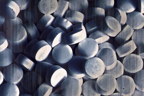 A close-up of numerous round, white tablets scattered across a surface.